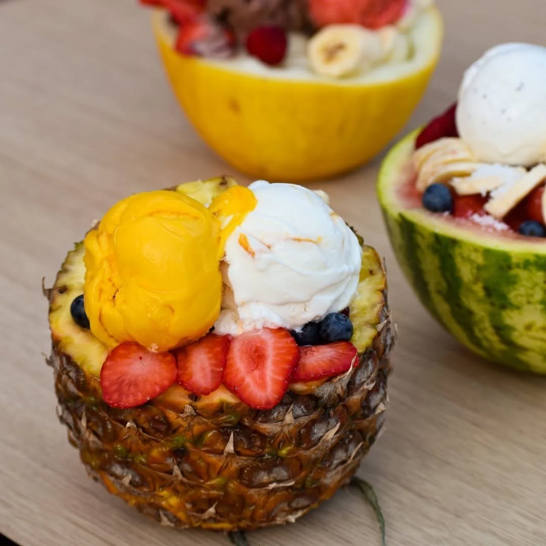 Ananás escavado com bolas de gelado, morangos e mirtilos
